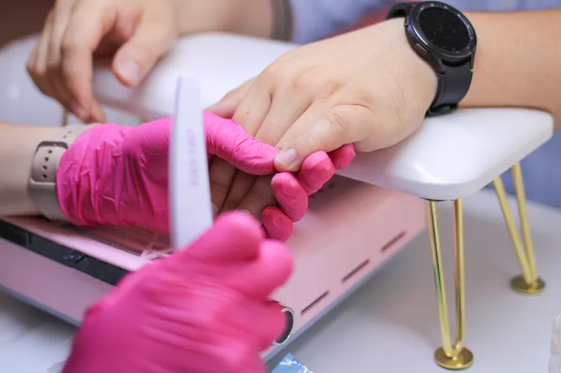 Manicurista limando las uñas de una clienta